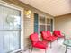 Front porch with red chairs, small table, and view of yard at 1509 Hollyberry Pl, The Villages, FL 32162