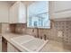 Kitchen sink with white cabinets and a mosaic backsplash at 1509 Hollyberry Pl, The Villages, FL 32162