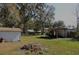 Large backyard featuring a detached garage, covered storage, and lush greenery, ideal for outdoor activities at 404 Cr 487, Lake Panasoffkee, FL 33538