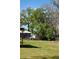 Grassy backyard with large trees, a shed, and partially fenced area, offering ample outdoor space at 404 Cr 487, Lake Panasoffkee, FL 33538