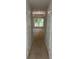 Hallway view leading into the bedroom with its carpet, trim, neutral walls, and large window looking at trees at 7 Nw 45Th Loop, Ocala, FL 34470