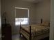 Serene bedroom featuring natural light from a window, complemented by a wooden bed frame and dresser at 10870 Sw 47Th Ct, Ocala, FL 34476