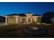 Single-story house exterior at night, featuring a red door and landscaping at 11545 Se 175Th St, Summerfield, FL 34491