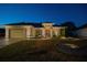 Single-story house exterior at night, featuring a red door and landscaping at 11545 Se 175Th St, Summerfield, FL 34491