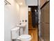 Compact bathroom featuring a pedestal sink, toilet, and glass-enclosed shower, adjacent to stairs and a modern kitchen at 13061 Se 158Th Ln, Weirsdale, FL 32195