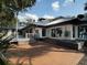 Rear exterior of a white modern house with a metal roof, patio, landscaping, and lake views at 13061 Se 158Th Ln, Weirsdale, FL 32195