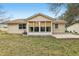 Tan house exterior with sunroom and patio, surrounded by a grassy yard at 1314 Noble Ct, Leesburg, FL 34788