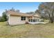 Tan house exterior with sunroom and partial view of backyard at 1314 Noble Ct, Leesburg, FL 34788