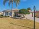 House exterior featuring a tan facade, lush landscaping, and a two-car garage at 13579 Se 89Th Terrace Rd, Summerfield, FL 34491