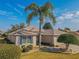 Single-story home with beige exterior, blue shutters, and palm trees at 13579 Se 89Th Terrace Rd, Summerfield, FL 34491