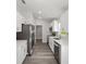 Galley kitchen featuring white cabinets, stainless steel appliances, quartz countertops, and gray wood-look flooring at 15304 Sw 27 Ln, Ocala, FL 34481