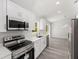 Well-equipped kitchen featuring stainless steel appliances, white cabinets, quartz countertops, and gray wood-look flooring at 15304 Sw 27 Ln, Ocala, FL 34481