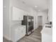 Modern kitchen featuring white cabinets, stainless steel appliances, quartz countertops, and gray wood-look flooring at 15304 Sw 27 Ln, Ocala, FL 34481