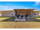 View of a covered back patio with a ceiling fan and a stone fire pit in the lawn at 1561 Ne 160Th Pl, Citra, FL 32113