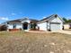 One-story house with attached garage, landscaping, and a blue front door at 22 Hemlock Trl, Ocala, FL 34472