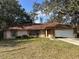 Single-story home featuring an attached garage, neutral paint, and a red shingle roof at 235 Oak Lane Loop, Ocala, FL 34472