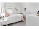 Bright bedroom with a white bed, pink accents, a window, and minimalist decor at 5450 Nw 46Th Lane Rd, Ocala, FL 34482