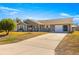 Single-story home with a long driveway, attached garage, and rocking chairs on the porch at 6490 Sw 84Th St, Ocala, FL 34476