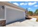 Attached two-car garage with light gray doors and stone accents at 8786 Sw 127 Ave, Dunnellon, FL 34432