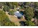 Birds-eye view of the home featuring a metal roof, palm tree and various outbuildings nestled within a treed lot at 9352 Ne 27Th Ter, Anthony, FL 32617