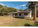 Rear exterior view of the home with a well-maintained lawn and surrounded by large shade trees at 9352 Ne 27Th Ter, Anthony, FL 32617