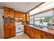 Sunlit kitchen featuring stainless sink, white appliances and wooden cabinetry at 9352 Ne 27Th Ter, Anthony, FL 32617