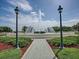 A serene fountain area with a paved walkway, manicured shrubs, and classic lampposts at 9651 Se 137Th Street Rd, Summerfield, FL 34491