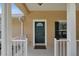 Charming front entrance featuring a teal door and a well-maintained porch with white railing at 12854 Se 118Th Ter, Ocklawaha, FL 32179