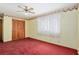 A bright bedroom featuring red carpet, ceiling fan, and a closet with wooden doors at 2145 Ne 45Th Ave # 2145, Ocala, FL 34470