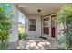 Covered front porch and entry with a red door and surrounding landscaping at 9014 Sw 96Th Ter, Ocala, FL 34481