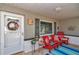 Inviting covered front porch featuring chairs, throw pillows, flower pots, and a wreath on the door at 9708 Sw 97Th St, Ocala, FL 34481