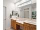 Dual sink bathroom with wood cabinets, a large mirror and decorative window above the mirror at 13100 Se 94Th Ave, Summerfield, FL 34491