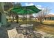 Cozy patio area with a round table, four chairs, and a large green umbrella for shade at 13100 Se 94Th Ave, Summerfield, FL 34491