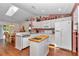 Charming kitchen featuring an island cooktop, white cabinetry, and a sunlit breakfast nook at 13370 Sw 112Th Pl, Dunnellon, FL 34432