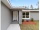 Close-up of a front door with white trim, framed by a gray exterior, and minimal landscaping at 13910 Sw 113 Ln, Dunnellon, FL 34432