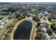 Scenic aerial view of a community with a lake, tennis court, and lush trees at 1517 New Abbey Ave, Leesburg, FL 34788