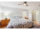 Bright bedroom with a ceiling fan, bed with patterned linens, two side tables and a glimpse into the bathroom at 1517 New Abbey Ave, Leesburg, FL 34788