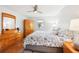 Bright bedroom with wood floors, a ceiling fan, dresser, and large bed dressed with floral patterned linens at 1517 New Abbey Ave, Leesburg, FL 34788