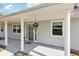 Inviting front porch with classic white columns, hanging flower basket, and stylish glass-paneled front door at 1517 New Abbey Ave, Leesburg, FL 34788