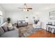 Open-concept living room featuring hardwood floors, a ceiling fan, and comfortable seating with stylish decor at 1517 New Abbey Ave, Leesburg, FL 34788