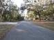 Paved road with mature, moss-draped trees and houses visible in the distance at 17840 Se 28Th Pl, Silver Springs, FL 34488