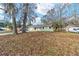 Inviting single-story home with lush trees, green paint, and a well-manicured front lawn at 6302 Nw 57Th Ave, Ocala, FL 34482