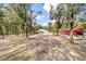 A wide shot of the backyard, showing the back of the home, and a red outbuilding, all surrounded by trees at 7670 Se 110Th Street Rd, Belleview, FL 34420