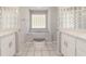 Bright bathroom featuring double sinks, tiled floors and a large glass block window at 7670 Se 110Th Street Rd, Belleview, FL 34420