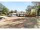 A wide shot of the front yard, showing a green lawn, mature trees, and home's neutral exterior at 7670 Se 110Th Street Rd, Belleview, FL 34420