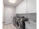 Laundry room with a modern washer and dryer, utility sink, and ample cabinet storage at 7670 Se 110Th Street Rd, Belleview, FL 34420