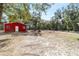 The red outbuilding stands out against a backdrop of lush trees, complementing the property's spacious outdoor setting at 7670 Se 110Th Street Rd, Belleview, FL 34420