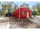 The striking red outbuilding with added shelter showcases the property's functionality and attention to outdoor storage at 7670 Se 110Th Street Rd, Belleview, FL 34420