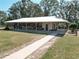 Exterior view of a long barn with stalls, a sidewalk, and a green door at 7688 Se 135Th St, Summerfield, FL 34491