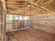 A stall in the tan barn featuring a metal gate, a wooden wall, and a dirt floor at 7688 Se 135Th St, Summerfield, FL 34491